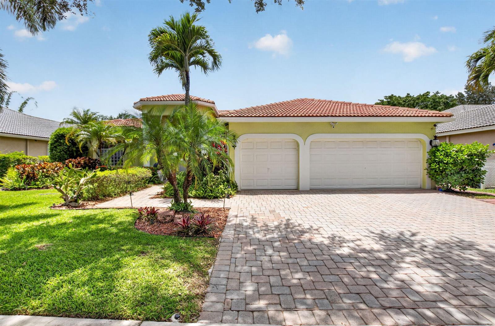 A light green house with a two-car garage and a paved driveway under a blue sky — 12657 Oak Run Court, Boynton Beach FL 33436, BOYNTON BEACH, FL