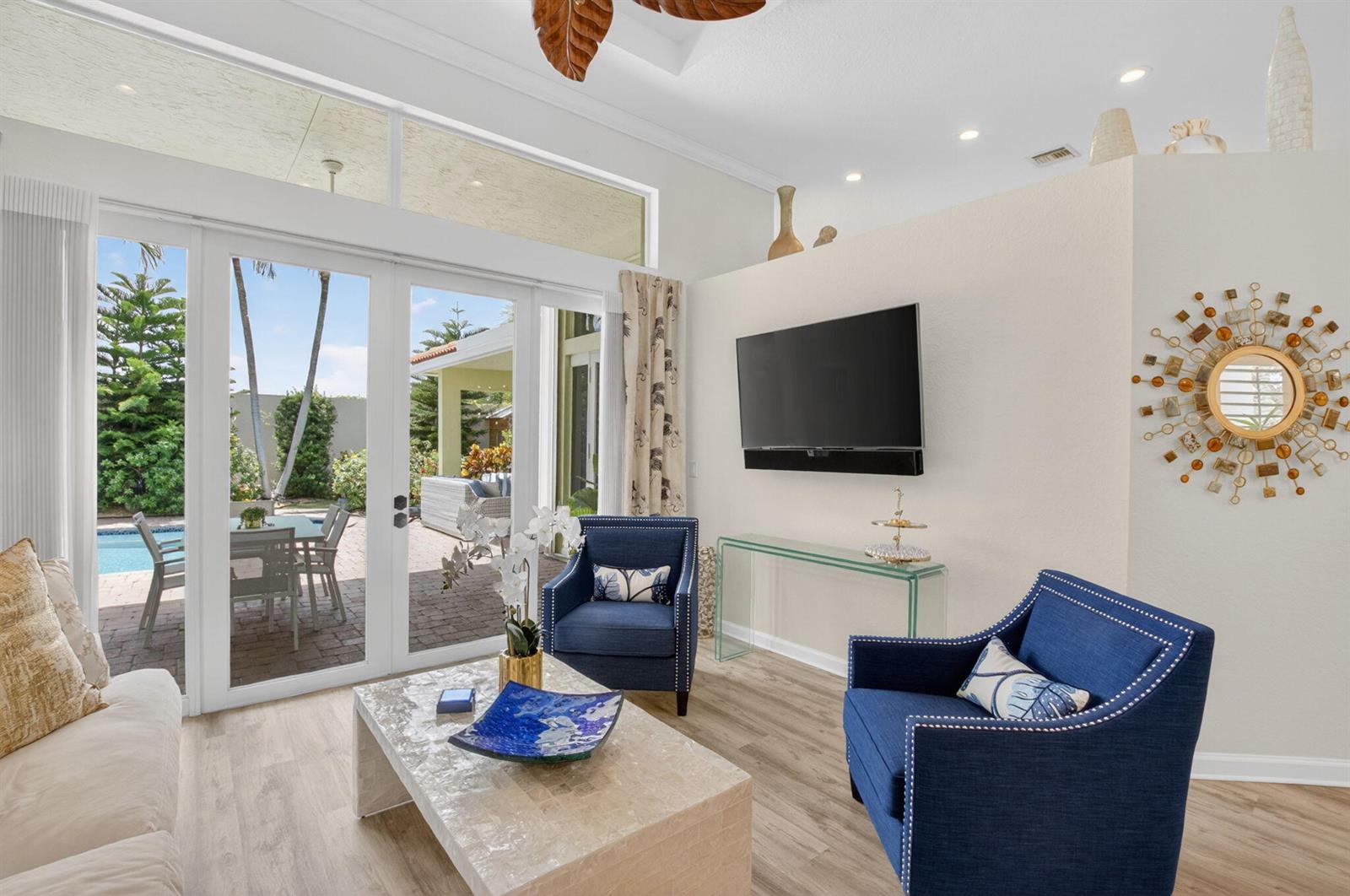 A living room features blue armchairs, a coffee table, a wall-mounted television, and glass doors — 12657 Oak Run Court, Boynton Beach FL 33436, BOYNTON BEACH, FL