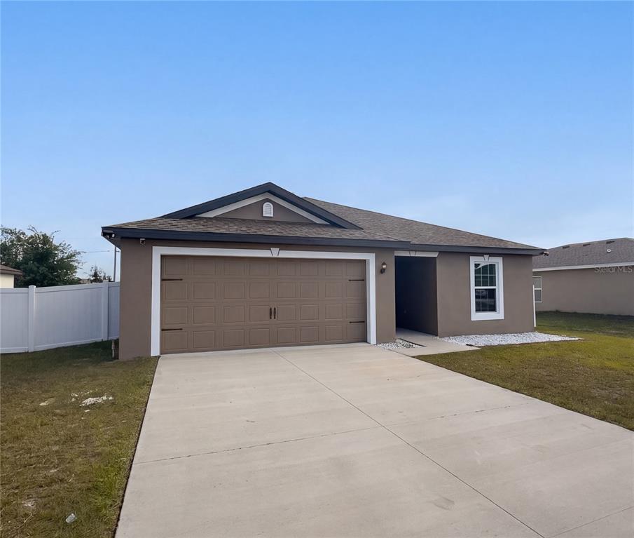 A single-story house with a brown exterior, a two-car garage, and a concrete driveway — 313 CAMELLIA COURT, POINCIANA, FL