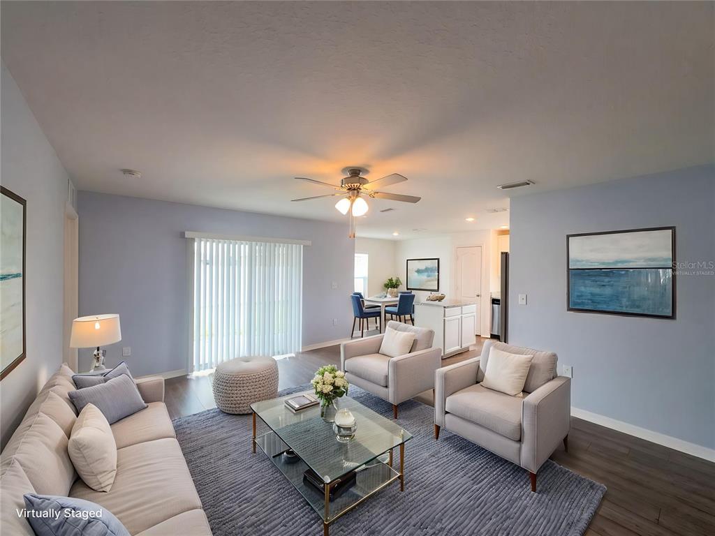 A living room with light blue walls, a glass coffee table, and two armchairs — 313 CAMELLIA COURT, POINCIANA, FL