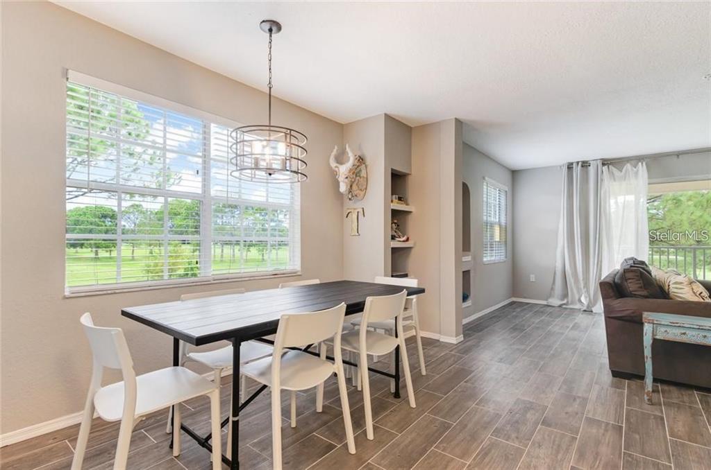 A dining area features a dark wood table, white chairs, and tile flooring — 13953 FAIRWAY ISLAND DRIVE UNIT 621, ORLANDO, FL