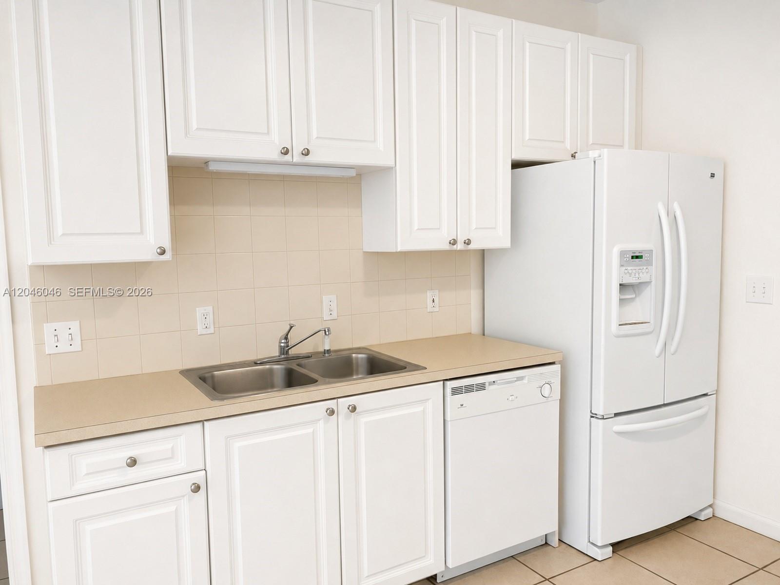 A kitchen features white cabinets, a double-basin sink, a dishwasher, and a white refrigerator — 4950 Washington St # 4, Hollywood FL 33021, HOLLYWOOD, FL