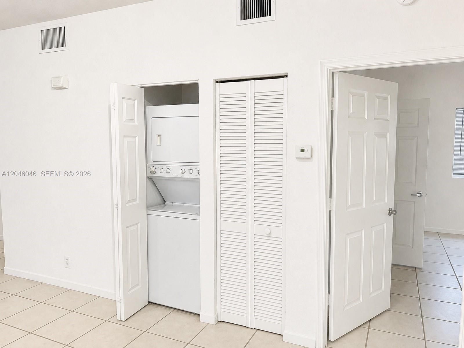 A white room features a stacked washer and dryer inside a closet next to a doorway — 4950 Washington St # 4, Hollywood FL 33021, HOLLYWOOD, FL