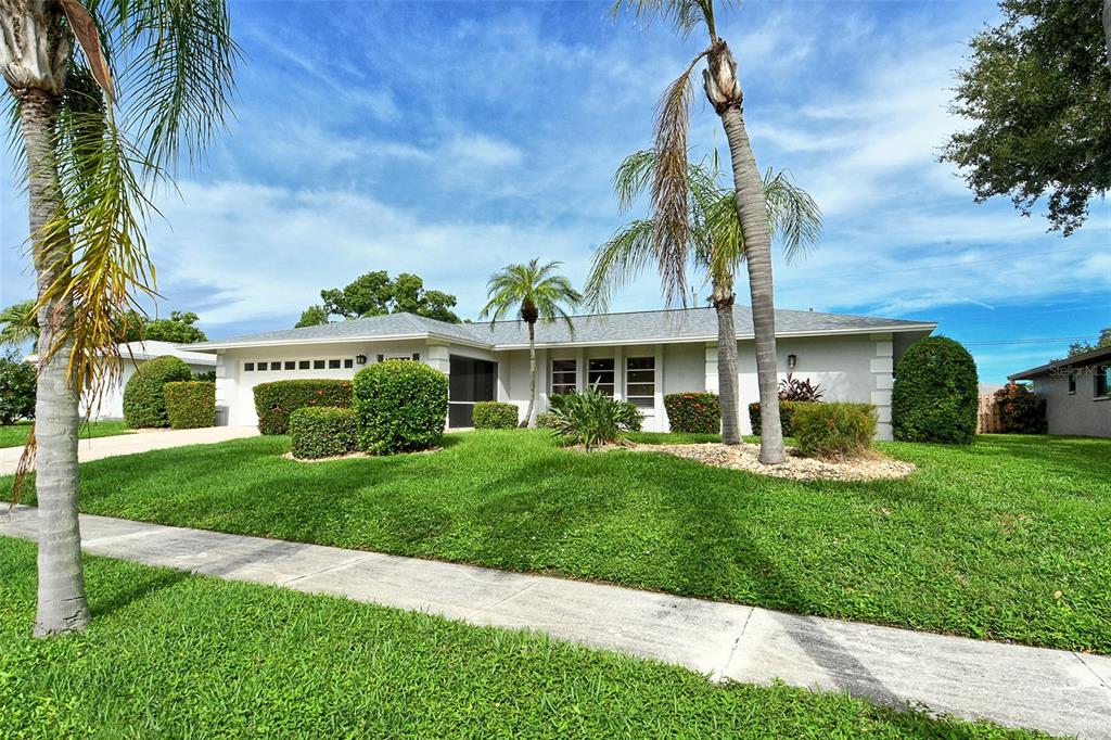 A single-story house with a light-colored exterior, palm trees, and a manicured lawn — 6722 ROXBURY DRIVE, SARASOTA, FL