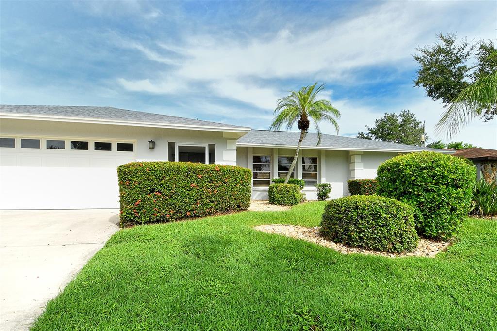 A single-story house with a white garage, manicured hedges, and a palm tree in front — 6722 ROXBURY DRIVE, SARASOTA, FL