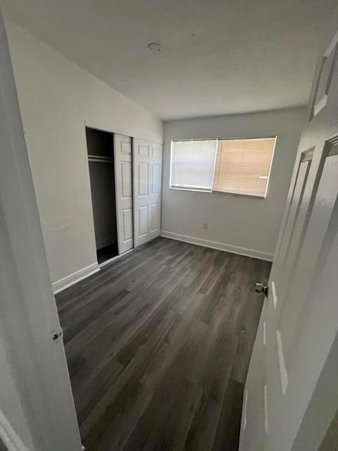 An empty bedroom features grey wood-look flooring, white walls, and a white sliding closet door — 3150 NW 3rd Street, Lauderhill FL 33311, LAUDERHILL, FL