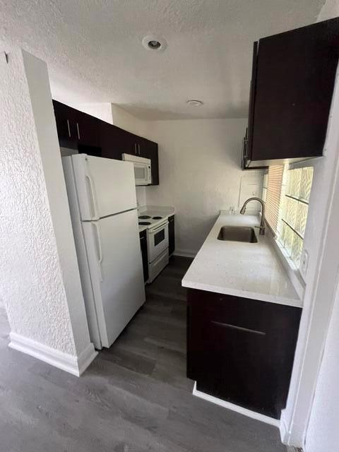 A galley kitchen features dark cabinets, white appliances, a stainless steel sink, and light flooring — 3150 NW 3rd Street, Lauderhill FL 33311, LAUDERHILL, FL