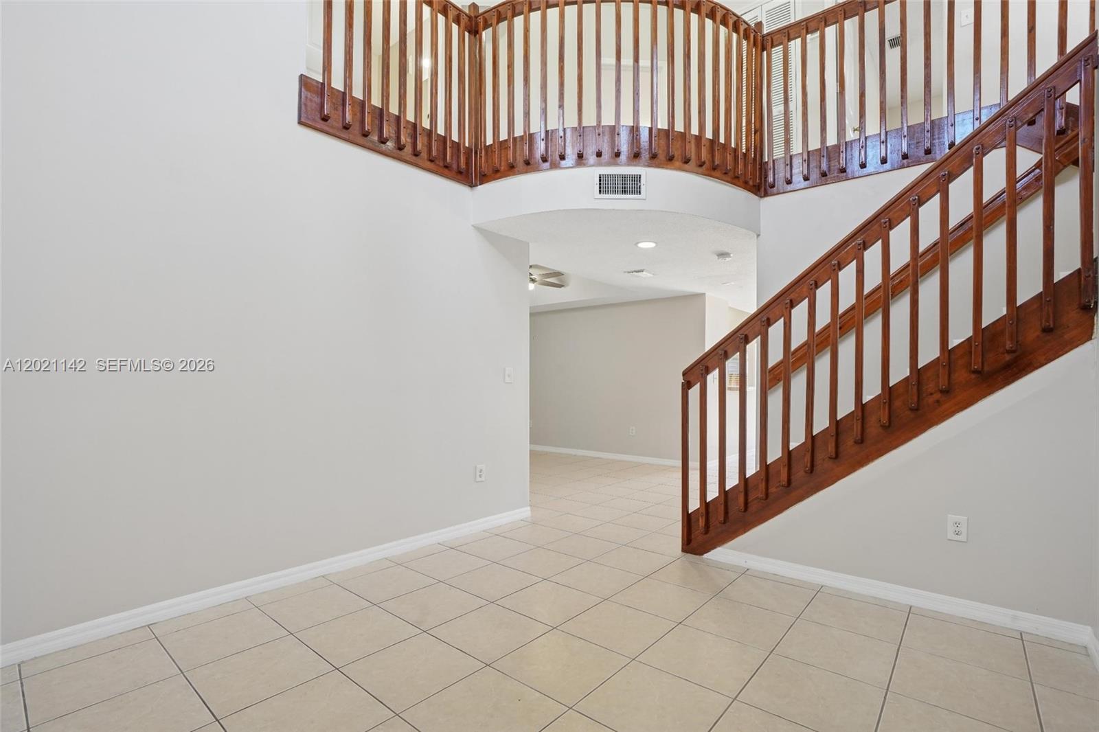 An entryway features light tile flooring, a wooden staircase, and a curved second-floor balcony railing — 8351 SW 124th Ave # 106, Miami FL 33183, MIAMI, FL