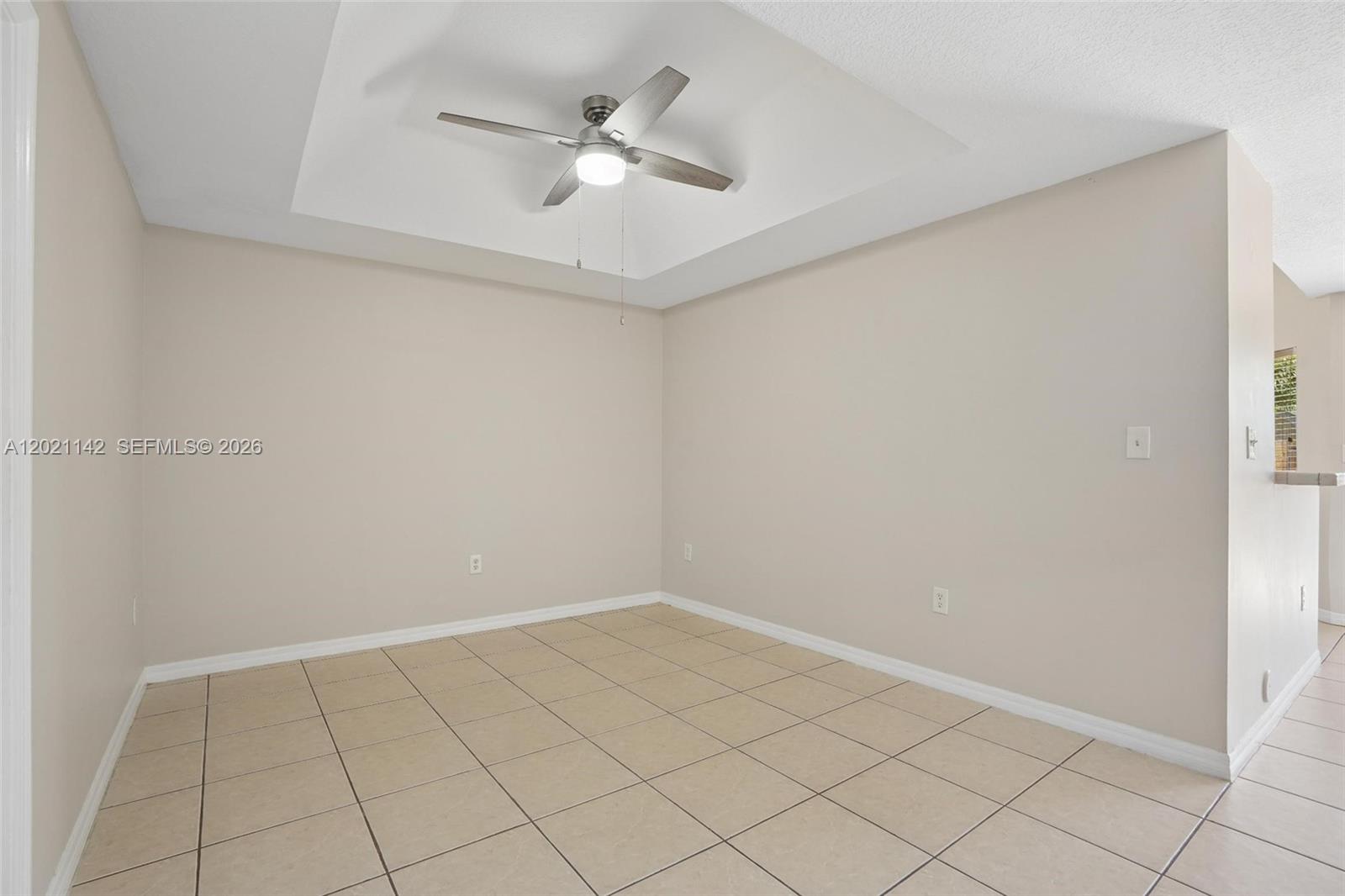 An empty room features beige walls, a tray ceiling with a fan, and tiled flooring — 8351 SW 124th Ave # 106, Miami FL 33183, MIAMI, FL