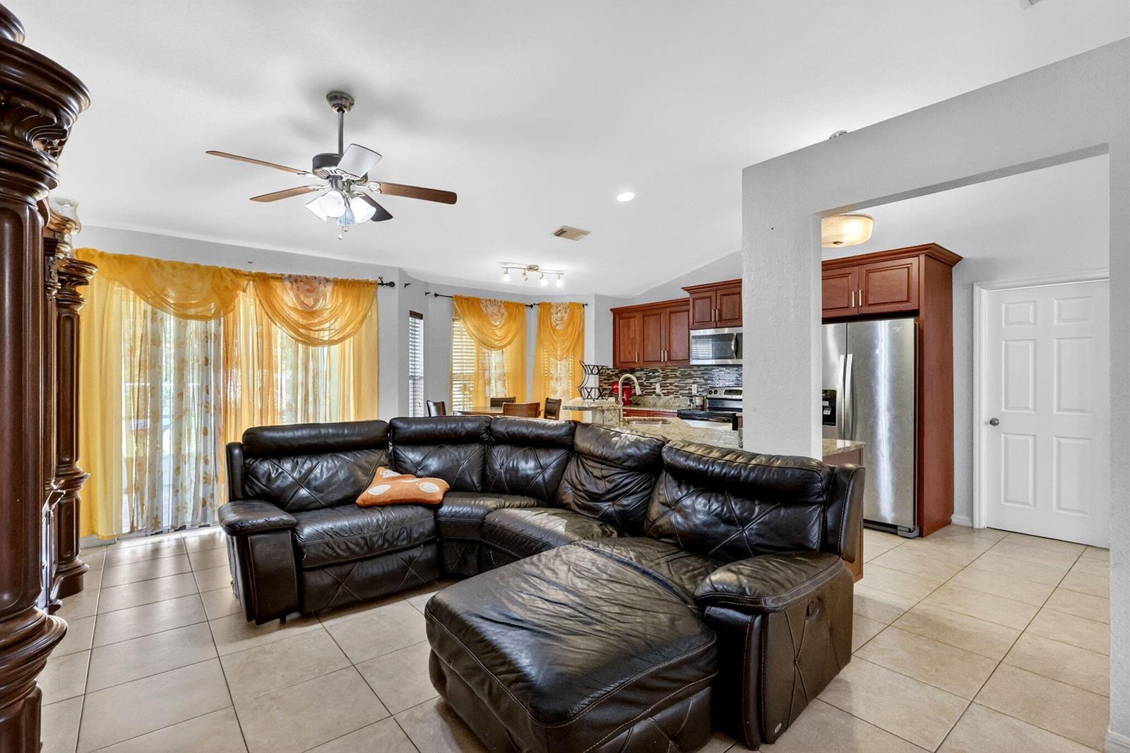 A living room with a dark leather sectional sofa opens into a kitchen with wood cabinets — 372 NW Hogan Street, FL 34983, FL