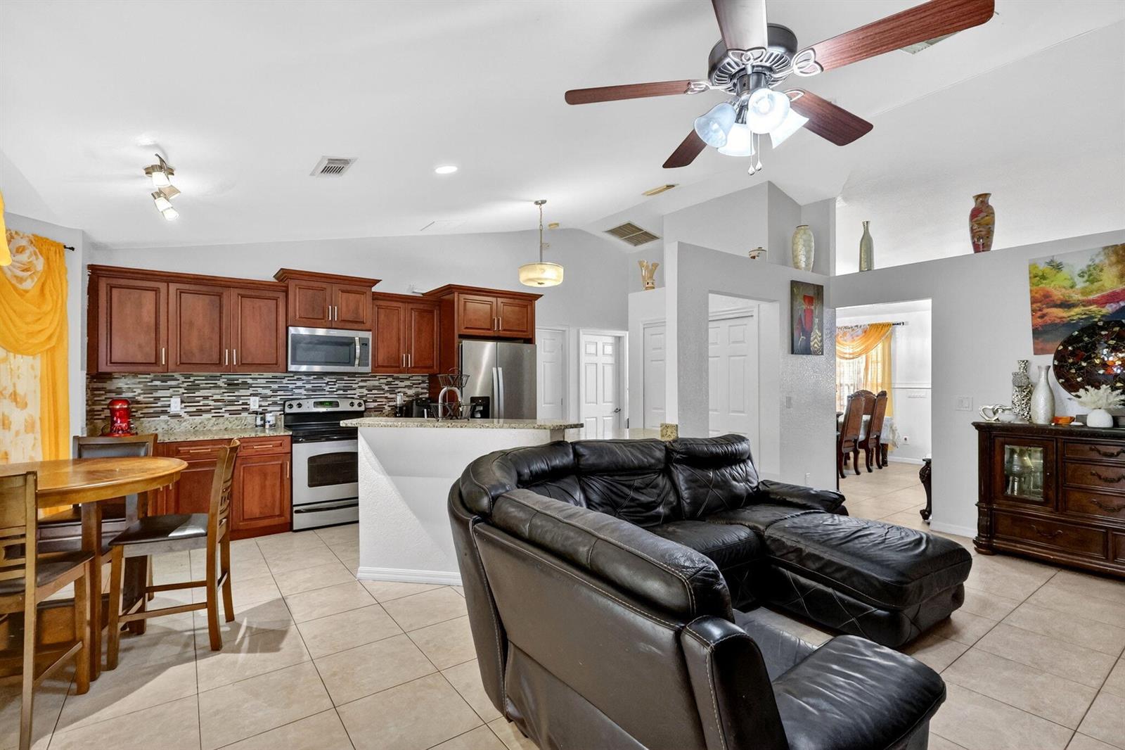 A kitchen with wood cabinets and a breakfast bar opens into a living room area — 372 NW Hogan Street, FL 34983, FL
