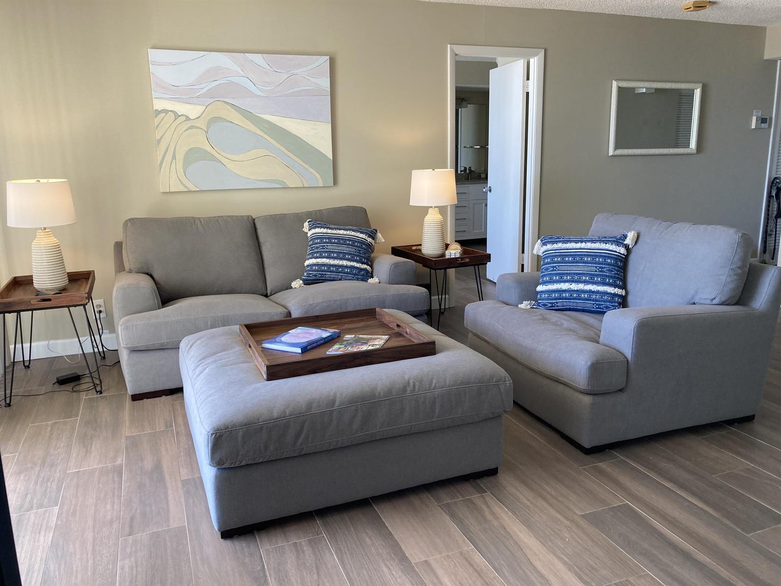 A living room features a gray sofa, armchair, large ottoman, and matching side tables — 300 Ocean Trail Way # 306, Jupiter FL 33477, JUPITER, FL