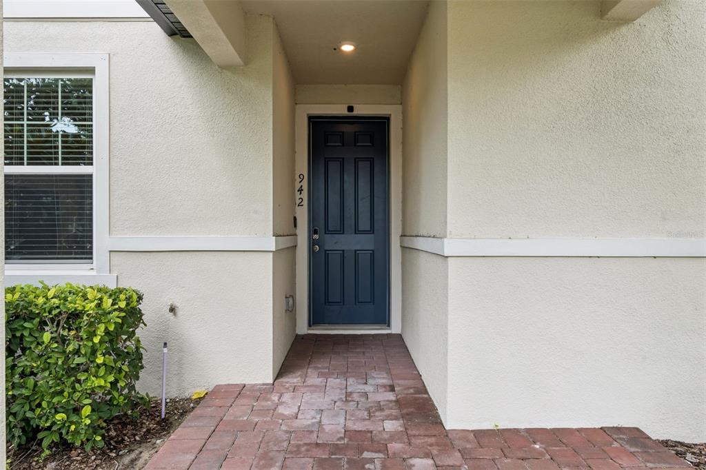 A dark blue front door with the number 942 sits under a covered entryway — 942 LEGACY WINDS WAY, CASSELBERRY, FL