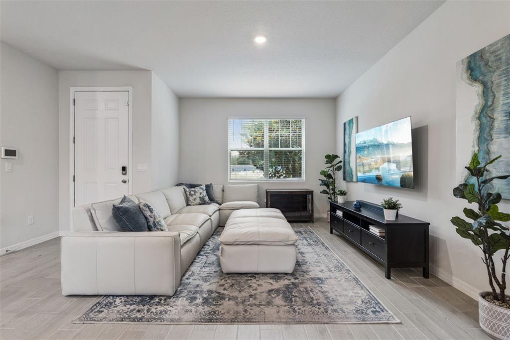 A living room features a white sectional sofa, a large area rug, and a wall-mounted television — 942 LEGACY WINDS WAY, CASSELBERRY, FL