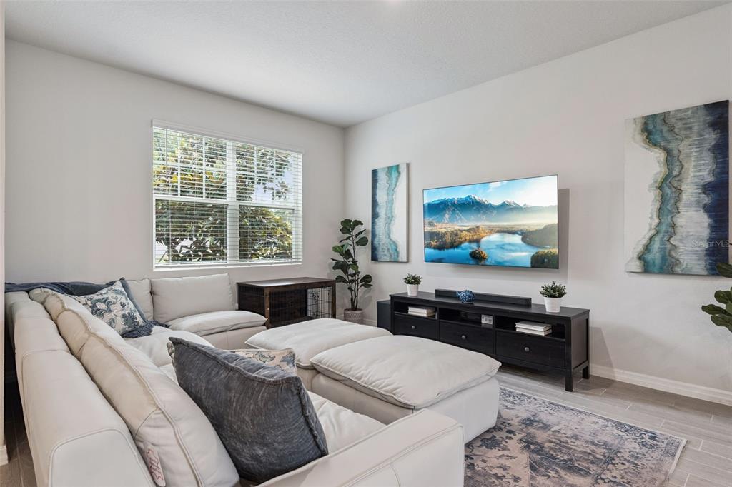 A living room features a large sectional sofa, a wall-mounted television, and abstract wall art — 942 LEGACY WINDS WAY, CASSELBERRY, FL