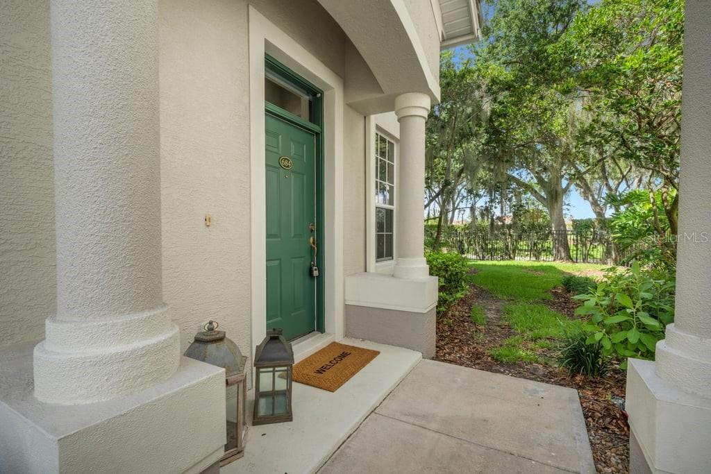 A front porch with a green door, two lanterns, and a welcome mat — 684 GRASSLANDS VILLAGE CIRCLE, LAKELAND, FL