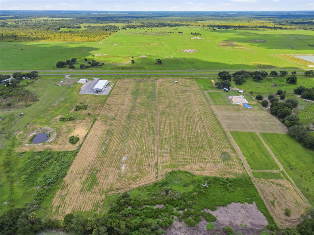 An aerial view shows a large, rectangular grassy field bordered by trees and a road — S US HWY 17, ZOLFO SPRINGS, FL
