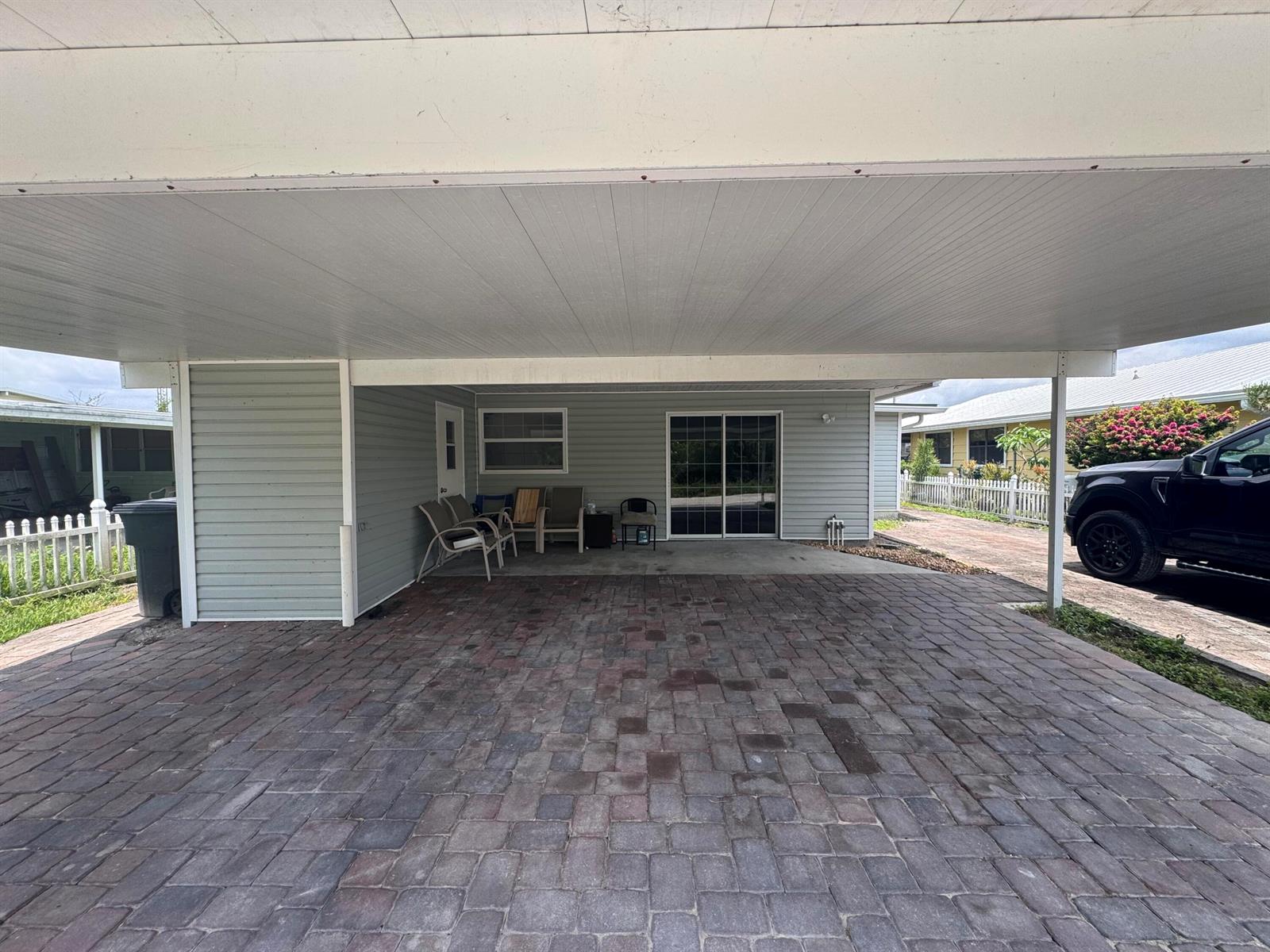 A paved carport leads to a house exterior with light gray siding and sliding doors — 14545 W Center Street, Okeechobee FL 34972, OKEECHOBEE, FL