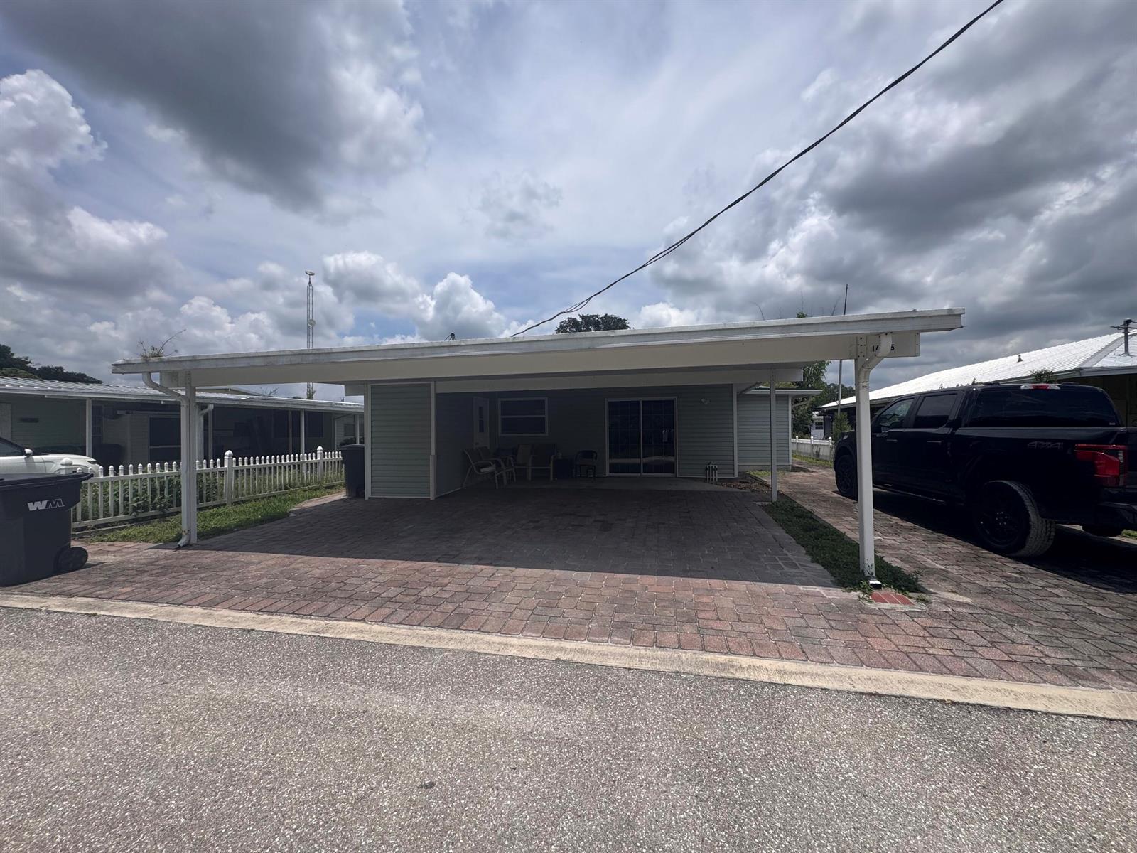 A paved carport with a white metal roof sits in front of a light-colored house — 14545 W Center Street, Okeechobee FL 34972, OKEECHOBEE, FL