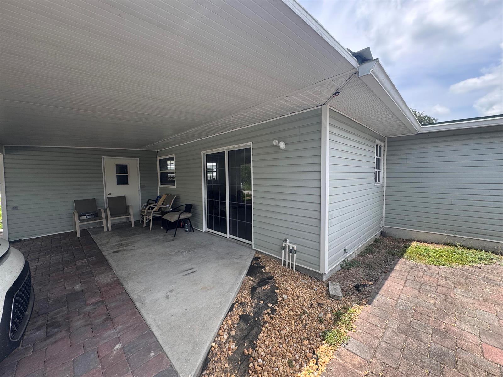 A covered patio features light green siding, a concrete floor, and a sliding glass door — 14545 W Center Street, Okeechobee FL 34972, OKEECHOBEE, FL
