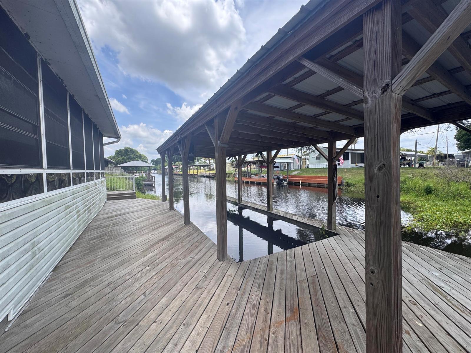 A wooden deck extends from a house to a covered boat slip over a canal — 14545 W Center Street, Okeechobee FL 34972, OKEECHOBEE, FL