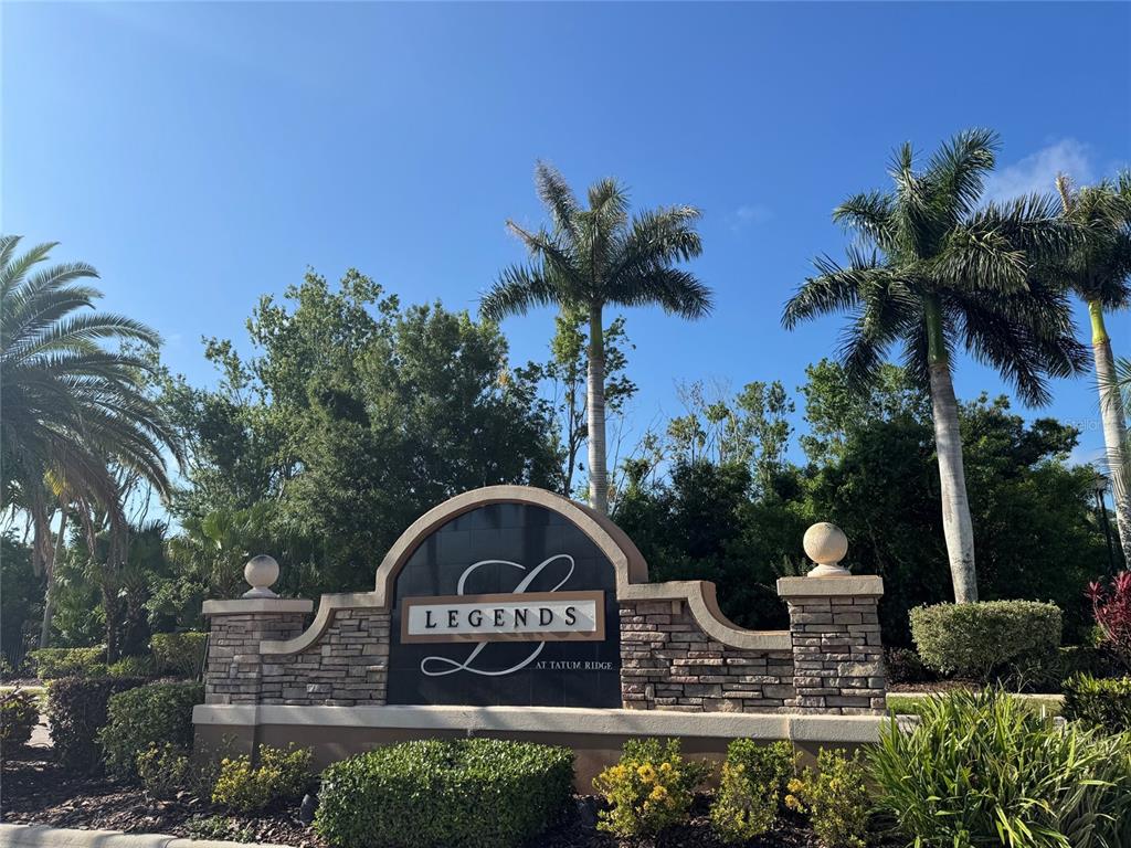 A stone monument sign for Legends at Tatum Ridge stands surrounded by palm trees — 7884 KAVANAGH COURT, SARASOTA, FL