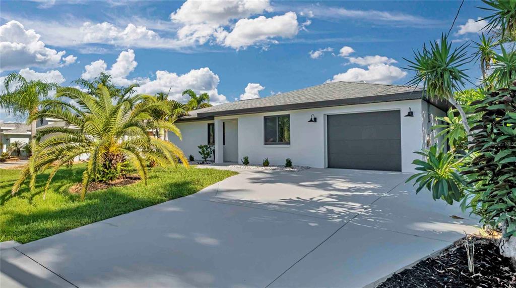 A single-story white house with a gray garage door and a palm tree in front — 15180 LYNEBURG AVENUE, PORT CHARLOTTE, FL
