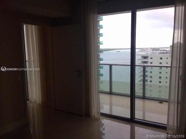 An interior room with tile floors, a closed door, and floor-to-ceiling windows overlooking the water — 1300 Brickell Bay Dr # 1707, Miami FL 33131, MIAMI, FL