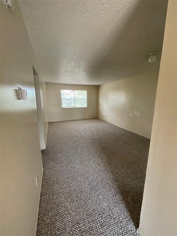 An empty room with beige walls, a textured ceiling, and gray carpeted flooring — 2192 KNOX MCRAE DRIVE UNIT N, TITUSVILLE, FL