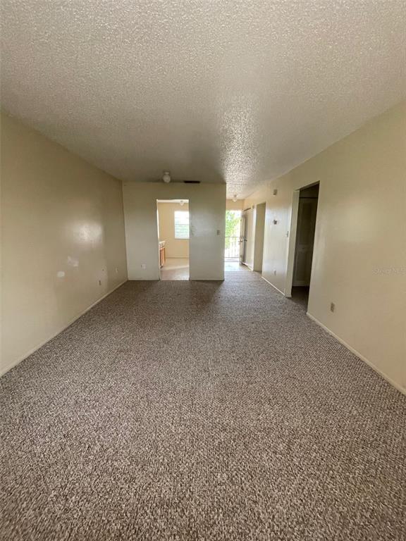 A carpeted living room leads to a kitchen and an exterior doorway — 2192 KNOX MCRAE DRIVE UNIT N, TITUSVILLE, FL
