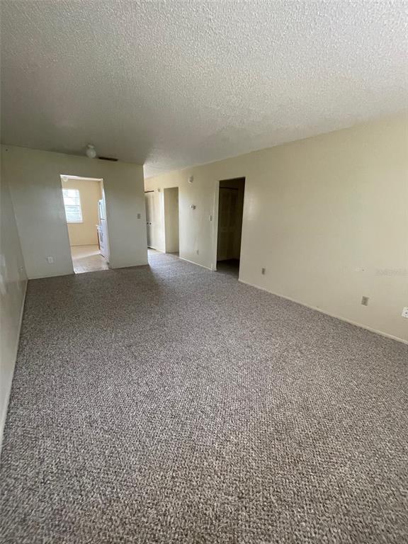 An empty living room with beige carpet, light-colored walls, and doorways leading to other rooms — 2192 KNOX MCRAE DRIVE UNIT N, TITUSVILLE, FL