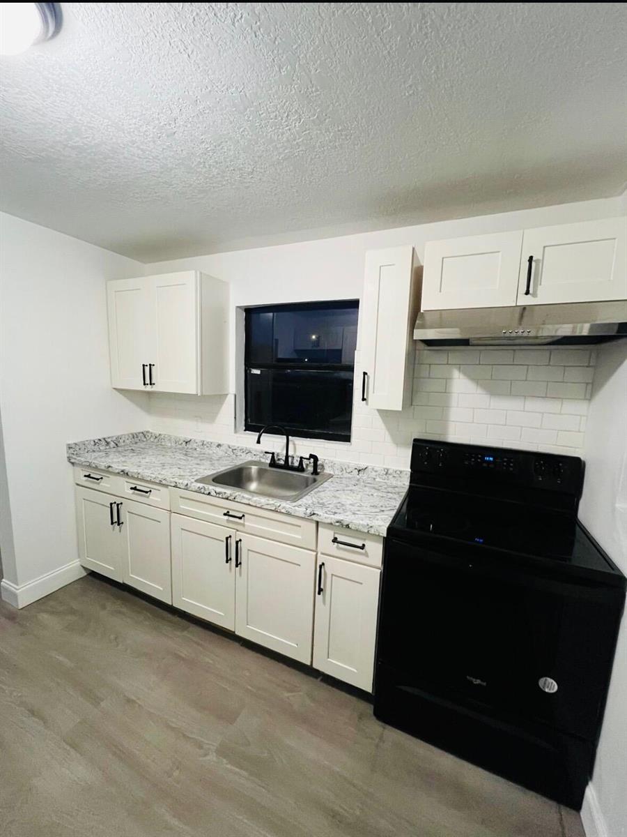 A kitchen features white cabinets, granite countertops, a black stove, and a subway tile backsplash — 515 S Wilson Avenue, Cocoa FL 32922, COCOA, FL