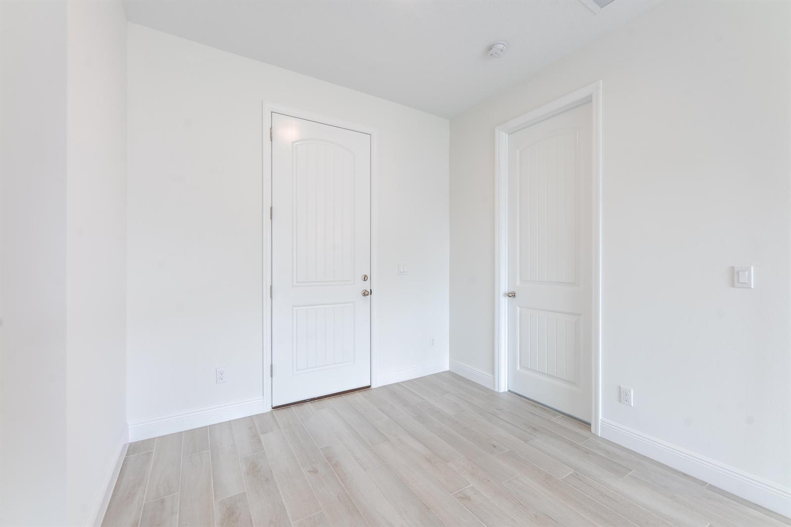 An empty room with white walls, light wood-look tile flooring, and two white doors — 5303 Sunset Boulevard, Fort Pierce FL 34982, FORT PIERCE, FL