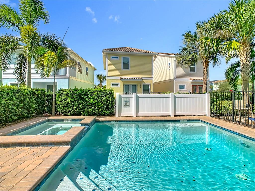 A swimming pool and hot tub sit in front of a yellow house with palm trees — 2946 SALTED RIM ROAD, KISSIMMEE, FL