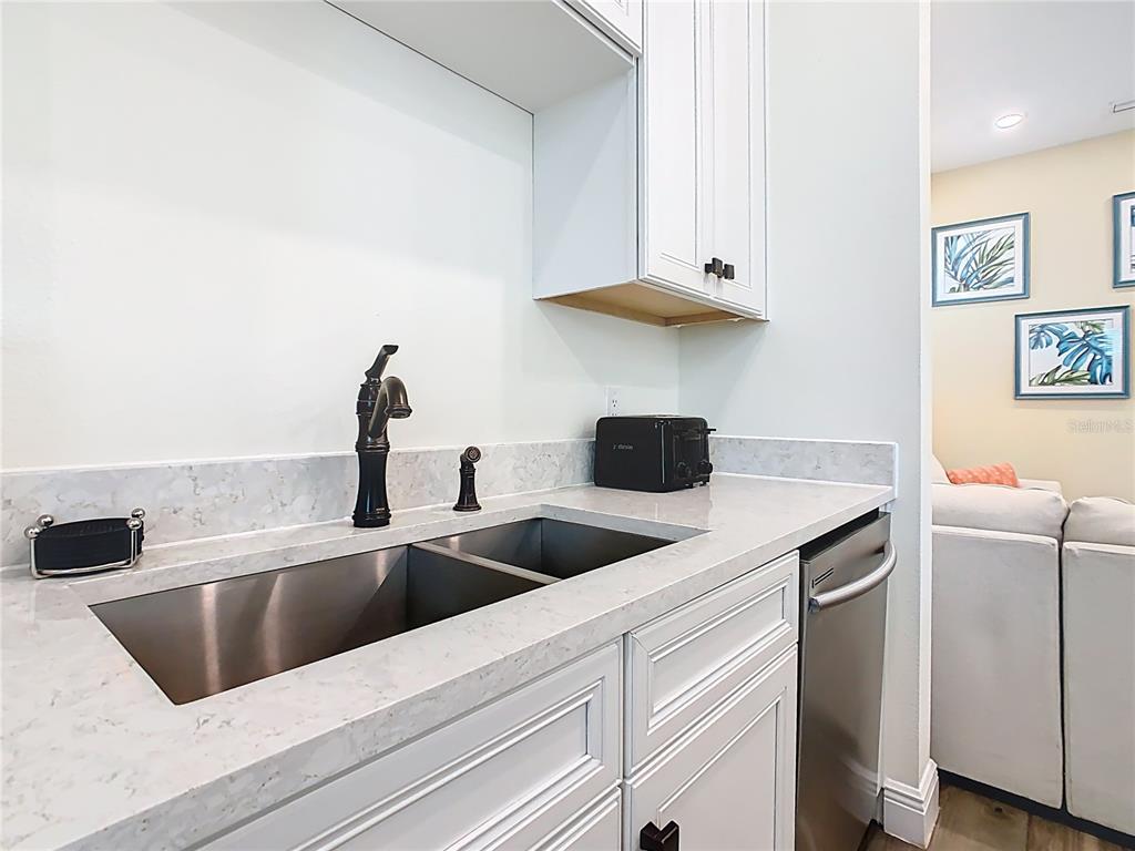 A kitchen sink area features white cabinets, a stainless steel sink, and light stone countertops — 2946 SALTED RIM ROAD, KISSIMMEE, FL