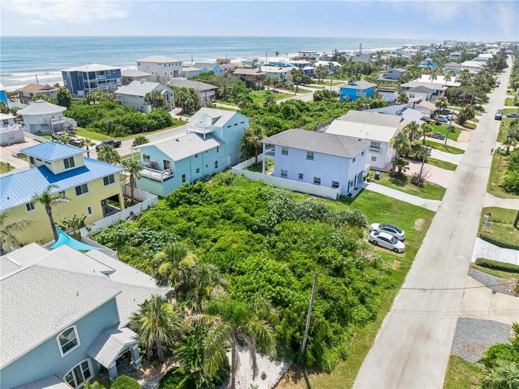 An aerial view shows a vacant, overgrown lot situated between several coastal residential homes — 6329 ENGRAM ROAD, NEW SMYRNA BEACH, FL