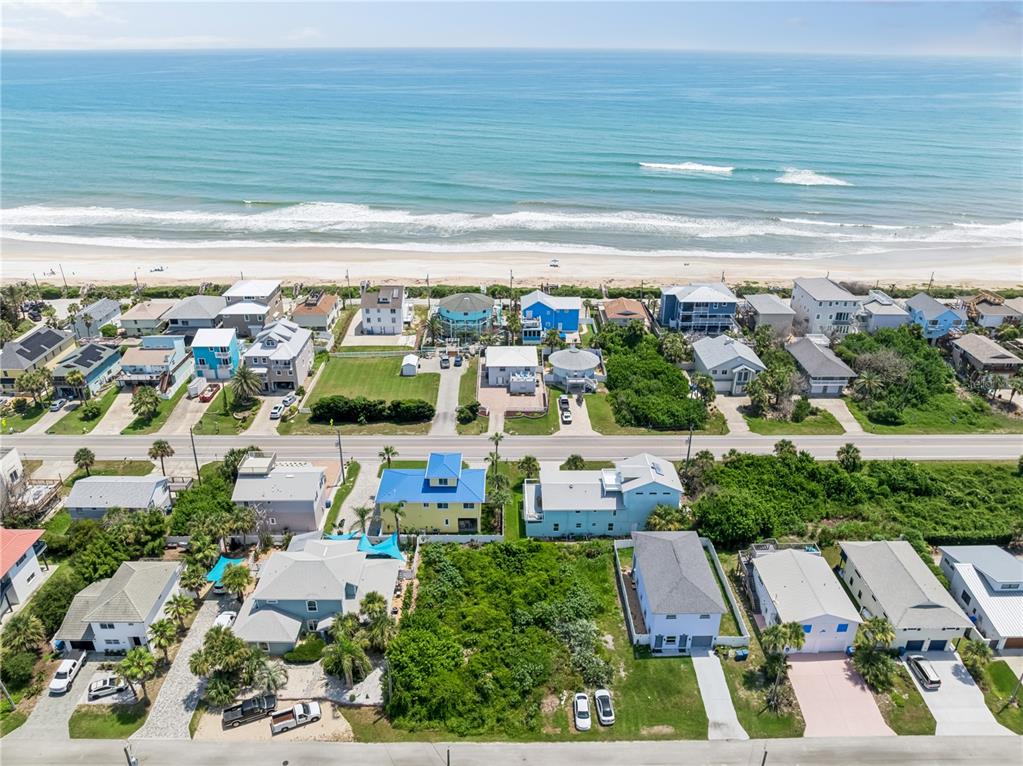 An aerial view shows a coastal neighborhood with houses situated along a beach — 6329 ENGRAM ROAD, NEW SMYRNA BEACH, FL