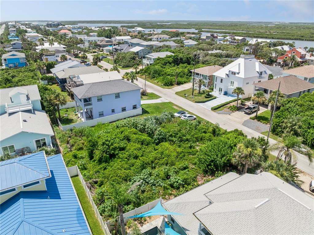 An aerial view shows a vacant, overgrown lot situated between several houses in a coastal neighborhood — 6329 ENGRAM ROAD, NEW SMYRNA BEACH, FL