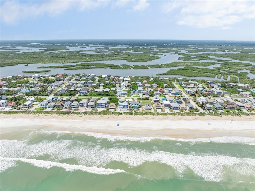 An aerial view shows a coastal neighborhood with houses situated between the ocean and wetlands — 6329 ENGRAM ROAD, NEW SMYRNA BEACH, FL