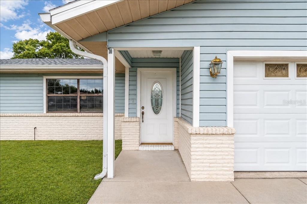 The exterior of a house features light blue siding, a brick base, and a white door — 4515 SE 59TH STREET, OCALA, FL