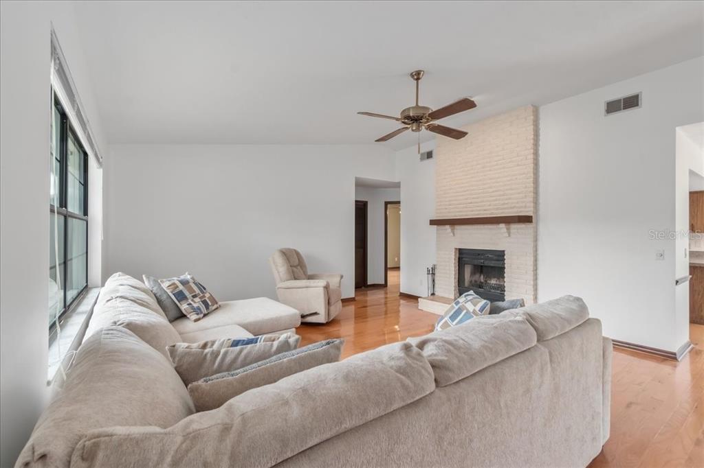 A living room features a white brick fireplace, hardwood floors, and a large sectional sofa — 4515 SE 59TH STREET, OCALA, FL