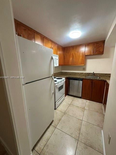 A kitchen features wood cabinets, a white refrigerator, a white stove, and tile flooring — 14250 SW 62nd St # 221, Miami FL 33183, MIAMI, FL