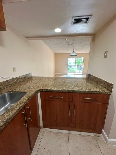A kitchen with granite countertops and wood cabinets overlooks a living area with a balcony — 14250 SW 62nd St # 221, Miami FL 33183, MIAMI, FL