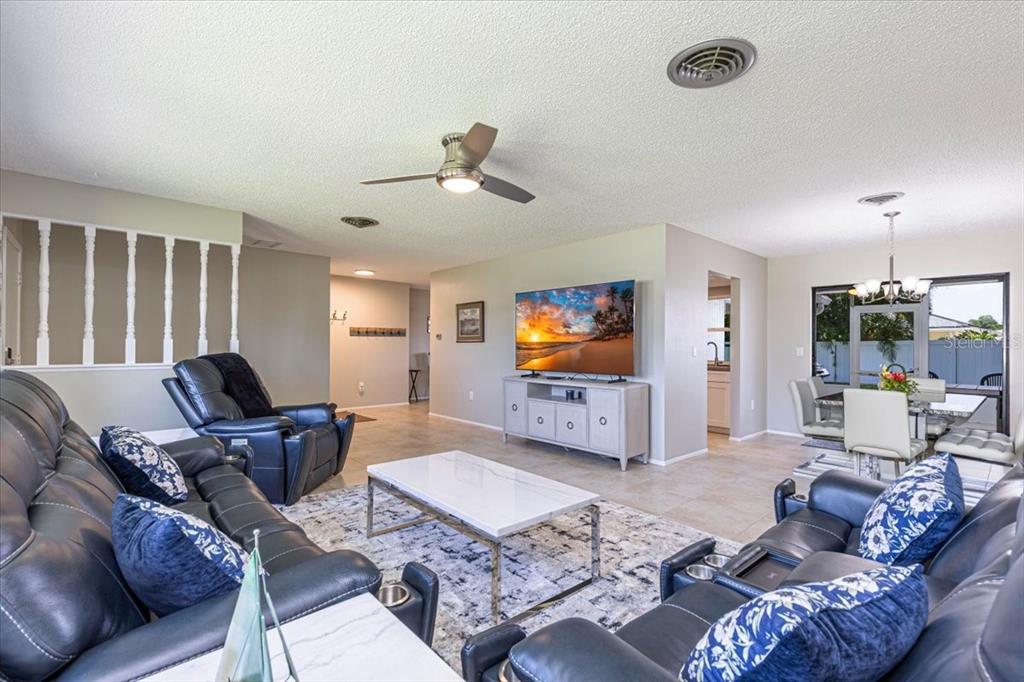 A living room features dark leather furniture, a white coffee table, and a television console — 1234 PINEBROOK WAY, VENICE, FL