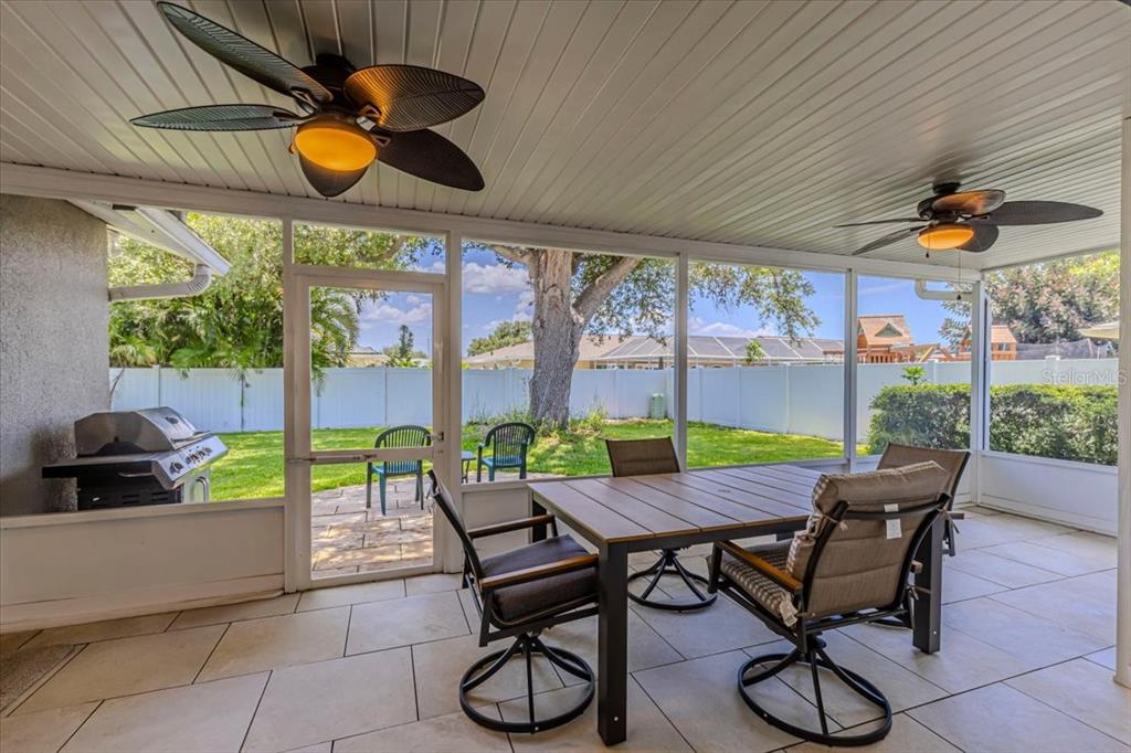 A screened-in patio features tile flooring, two ceiling fans, a dining set, and a grill — 1234 PINEBROOK WAY, VENICE, FL