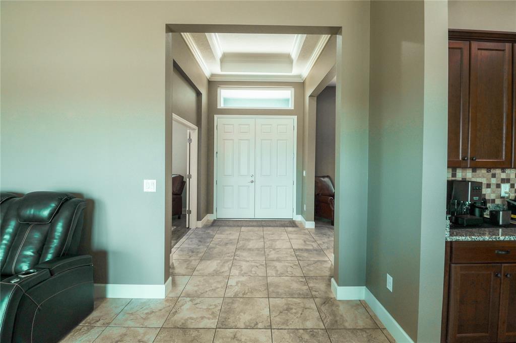 A tiled entryway features a double front door, a tray ceiling, and adjacent living spaces — 5054 LAKE TOSCANA DRIVE, WIMAUMA, FL
