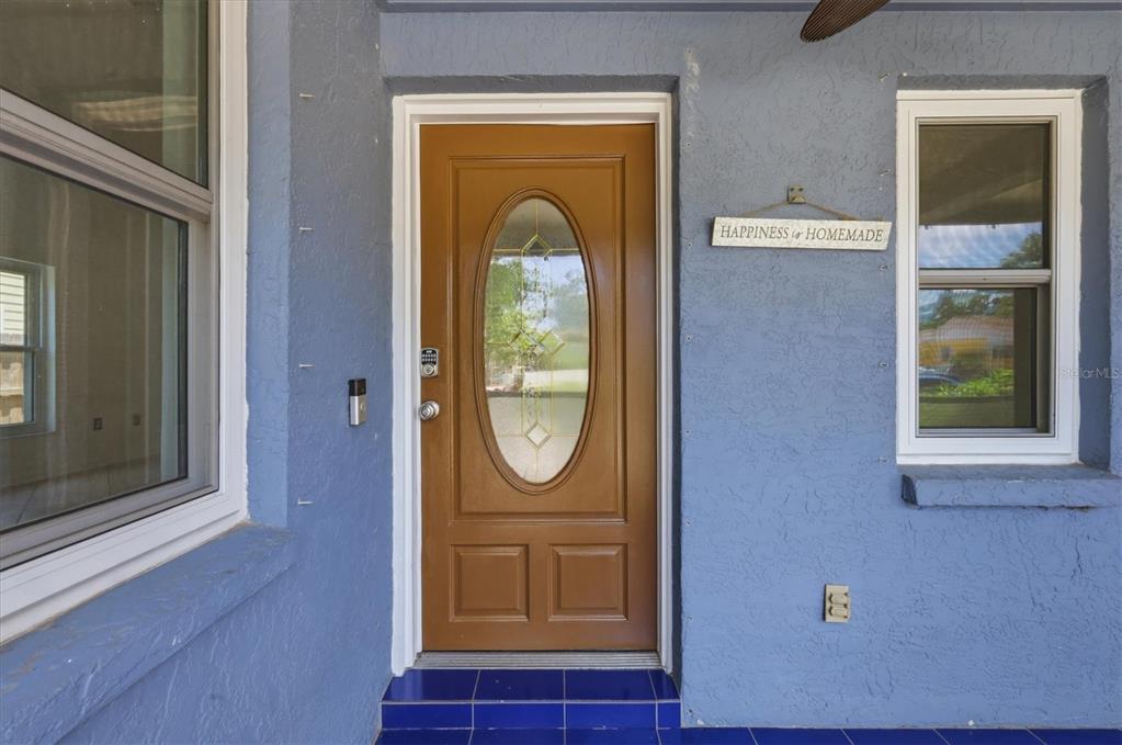 A blue stucco exterior wall features a brown front door with an oval glass insert — 1649 8TH STREET, SARASOTA, FL