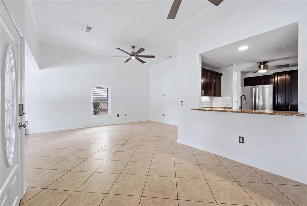 An open-concept living area with tile flooring, vaulted ceilings, and a kitchen pass-through window — 1649 8TH STREET, SARASOTA, FL