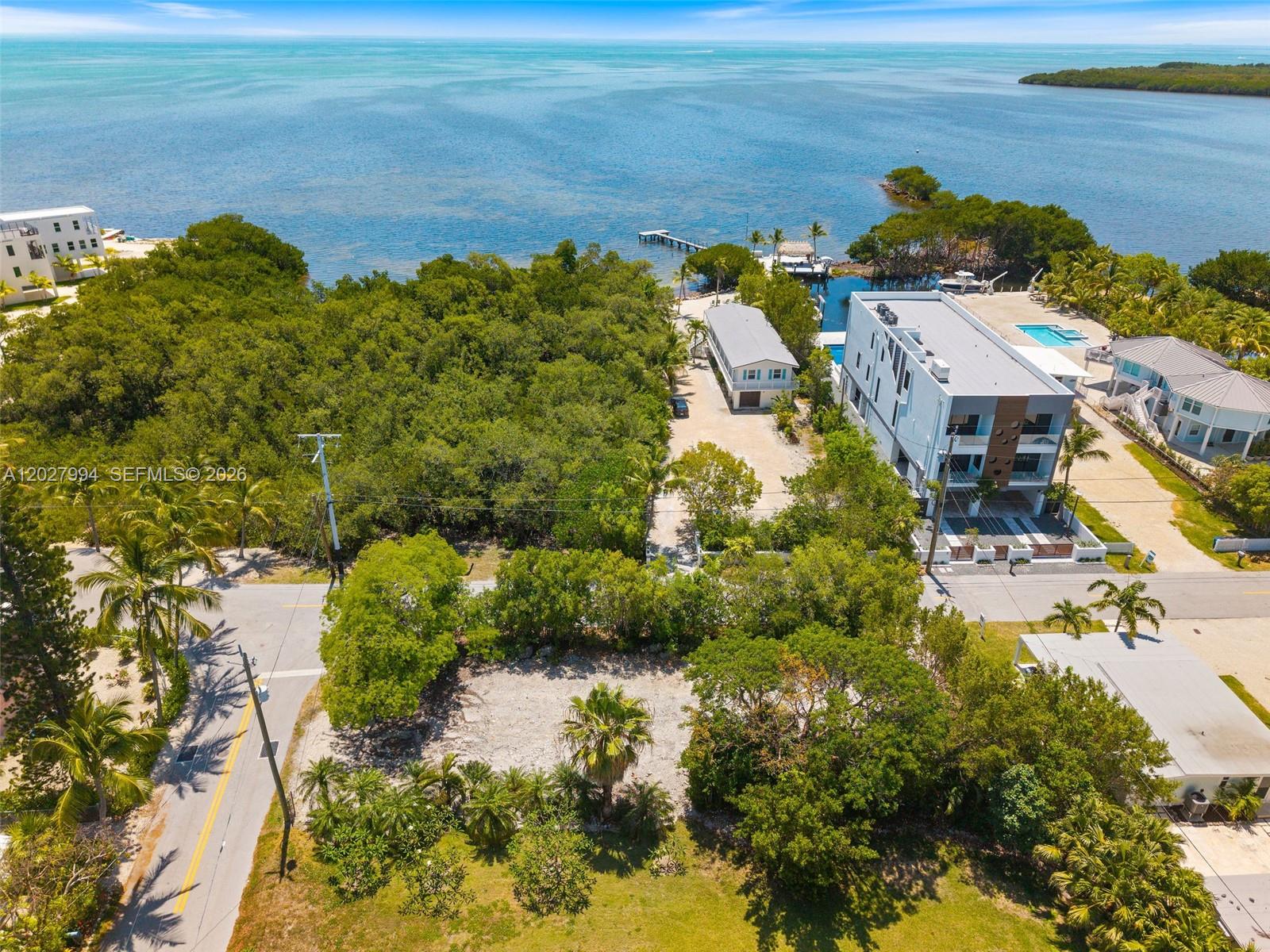 An aerial view shows a vacant lot near a modern building and the ocean — 0 Seaside Ave, Key Largo FL 33037, KEY LARGO, FL