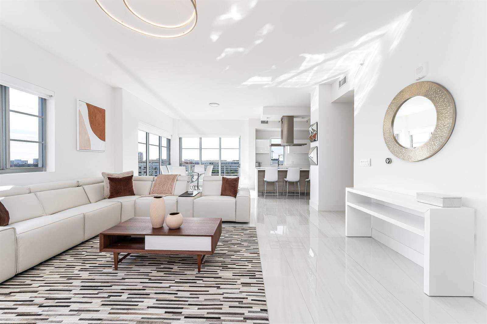 A modern living room with a white sectional sofa, wood coffee table, and tile flooring — 155 E Boca Raton Road # 1103, Boca Raton FL 33432, BOCA RATON, FL